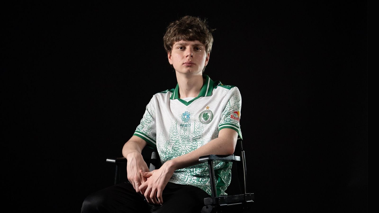 Team Falcons CS2 player kyousuke sitting on a chair while looking fiercely at the camera on a black background.